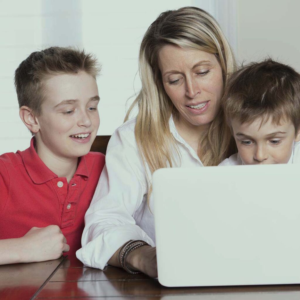 madre y dos hijos de unos 6 y 11 años consultan algo en un ordenador.