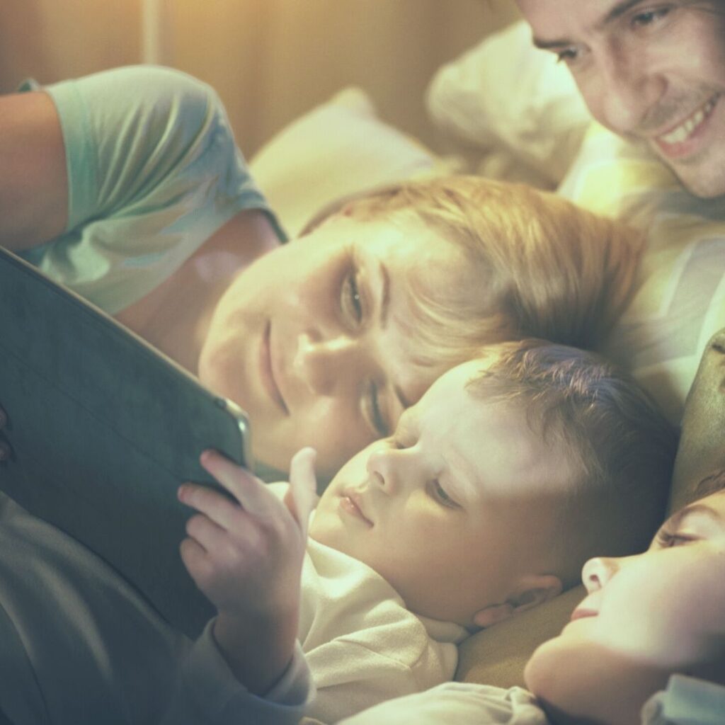 Una familia madre, padre y dos niños miran una tablet