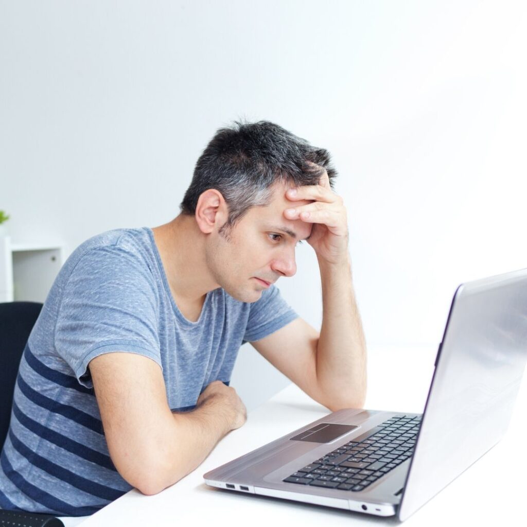 Hombre adulto frente a un ordenador con cara de preocupación